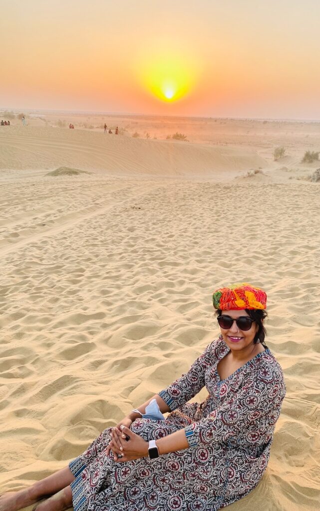 A beautiful sunset in Thar desert, Rajasthan, India. A girl sitting in the desert by sunset